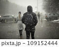 Snow in city. Heavy snow is falling outside. Blurry silhouettes of people in blizzard. 109152444