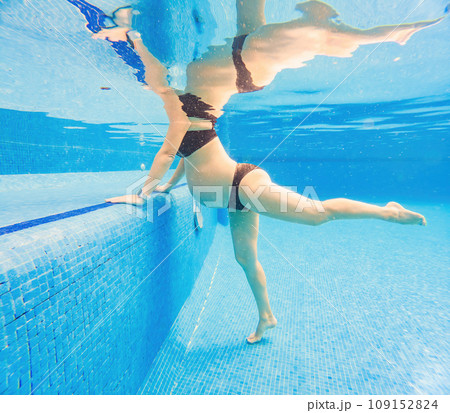 Embracing aquatic fitness, a pregnant woman demonstrates strength and serenity in underwater aerobics, creating a serene and empowering image in the pool 109152824