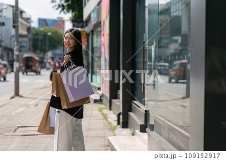 Young asian woman in shopping. Fashion woman in black with shopping bag walking around the city after shopping. Black friday 109152917