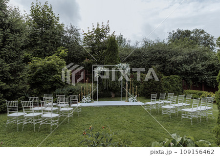 Beautiful wedding arch decorated with flowers and chairs for guests Beautiful wedding arch decorated with flowers and chairs for guests 109156462
