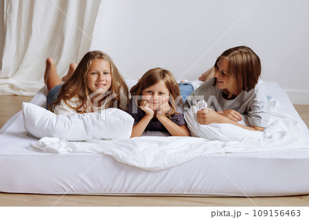 Sisters lying on a bed in their home smmiling for the camera. Sisters lying on a bed in their home smmiling for the camera. 109156463