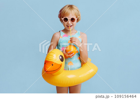 Child with inflatable duck ring on blue background with copy space. 109156464