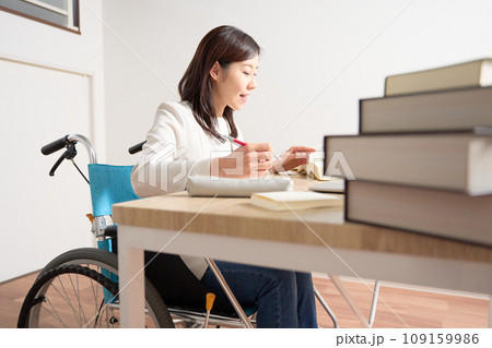 デスクで勉強している車椅子の女性 109159986