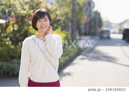 住宅街を歩く笑顔の50代の女性 住宅街を歩く笑顔の50代の女性 109160602