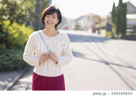 住宅街を歩く笑顔の50代の女性 住宅街を歩く笑顔の50代の女性 109160603