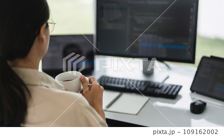 Developer programmer drinking coffee and checking code on monitor for programming to developing web 109162002