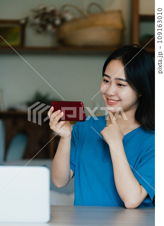 スマホで動画視聴をする若い女性 スマホで動画視聴をする若い女性 109163010