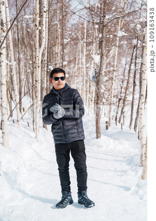 happy Traveler with Sweater walking on snow covered forest in frosty weather. Winter Travel, Adventure, Exploring and Vacation concept 109163438