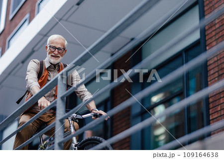Elderly man, cyclist traveling through the city by bike. Senior city commuter riding a bike to grocery store. 109164638