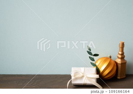 Christmas decoration ornament golden ball, gift box on wooden table. blue wall background 109166164