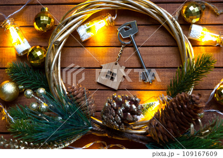 Key to house with a keychain tiny home on wooden background with Christmas decor layout. Gift for New Year, Christmas. Building, project, moving to new house, mortgage, rent and purchase real estate Key to house with a keychain tiny home on wooden background with Christmas decor layout. Gift for New Year, Christmas. Building, project, moving to new house, mortgage, rent and purchase real estate 109167609