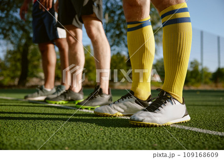 Football player legs standing on white line dividing football field Football player legs standing on white line dividing football field 109168609