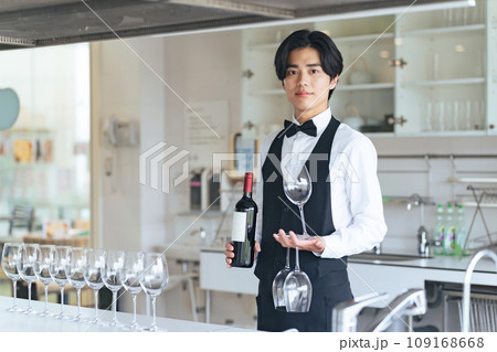 ワインボトルとワイングラスを運ぶ男性 109168668
