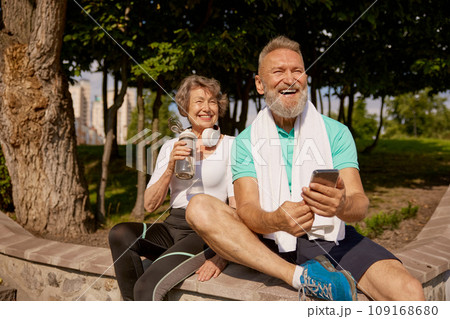 Happy overjoyed elderly man and woman couple enjoying sunny day after jogging 109168680