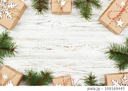Christmas composition. Christmas gift, knitted blanket, pine cones, fir branches on wooden white background. Flat lay, top view 109169445