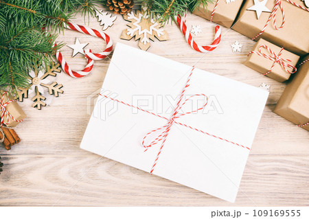 Parcel in Envelope with Fir-tree Branches and christmas decoration on a Wooden Background. Toned Parcel in Envelope with Fir-tree Branches and christmas decoration on a Wooden Background. Toned 109169555