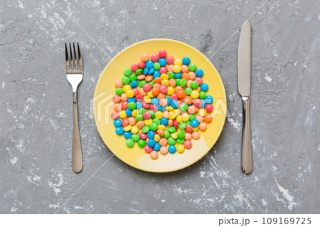 cutlery on table and sweet plate of candy. Health and obesity concept, top view on colored background 109169725