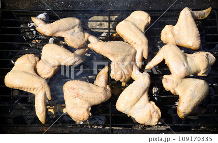 Raw chicken wings marinated in sour cream and spices, grilling on the grill grate. Start cooking, barbecue 109170335