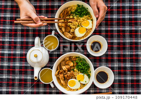Piece of chicken in chopsticks with japanese ramen and males hands 109170448