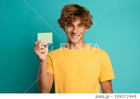 Teen age boy holds creit card on bright color background 109172448