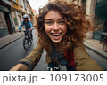 Beautiful young woman riding a bike in old town 109173005