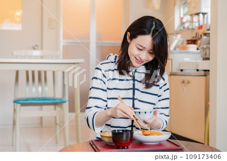質素な家でごはんを食べる一人暮らしの女性 質素な家でごはんを食べる一人暮らしの女性 109173406
