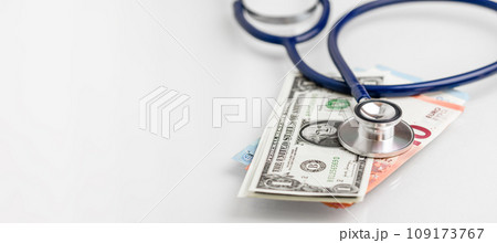 Stethoscope lying on various Euro and US banknotes. Medical cost, insurance, wealth, health, education concept. 109173767