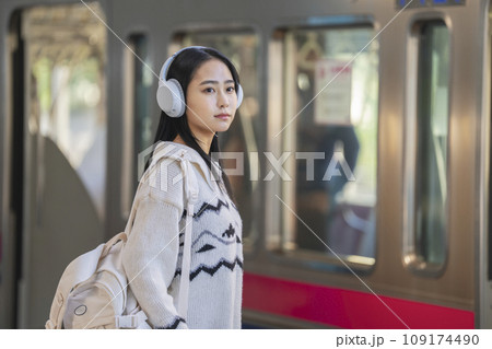 ホームで電車を待つヘッドホンをつけた若い女性　撮影協力「京王電鉄株式会社」 109174490