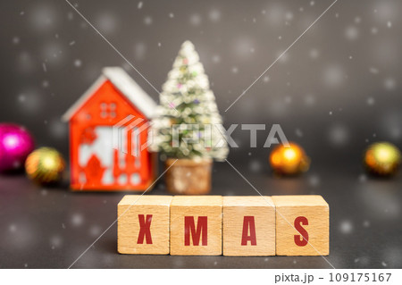 Wooden blocks with the word Xmas, miniature house and a Christmas tree. New Year or Xmas winter holiday. Decoration, celebration. The concept of the beginning of the new year. Snow, snowfall 109175167