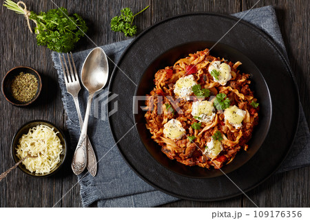 Lasagnette with beef ragu, mushrooms and ricotta cheese in black bowl on dark wooden table Lasagnette with beef ragu, mushrooms and ricotta cheese in black bowl on dark wooden table 109176356