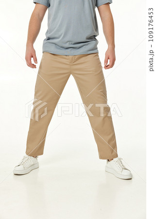 man wearing white sneakers and casual beige pants on studio background, front view 109176453