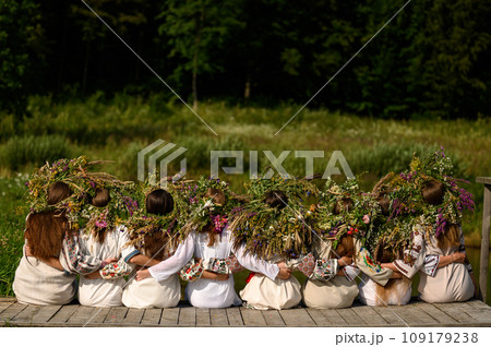 Girls in woven wreaths of different flowers and grass on a warm summer day. Girls in woven wreaths of different flowers and grass on a warm summer day. 109179238
