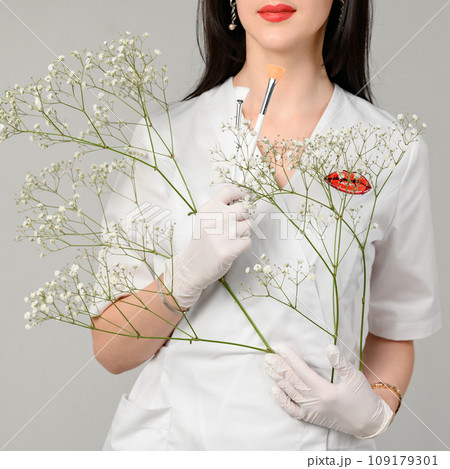 the doctor cosmetologist holds two brushes in her hands on a white background the doctor cosmetologist holds two brushes in her hands on a white background 109179301