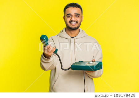 Indian man talking on wired landline vintage telephone, advertising proposition of conversation 109179429
