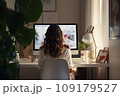 Young woman working from home in front of a computer monitor. The apartment is minimalistic, with plants 109179527