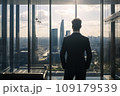 Young businessman standing in front of an office window, overlooking the city skyline 109179539