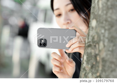 隠れてスマホで撮影する女性 隠れてスマホで撮影する女性 109179768