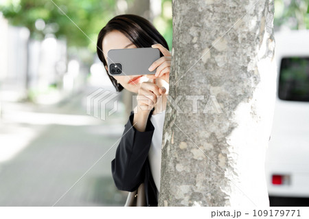 隠れてスマホで撮影する女性 隠れてスマホで撮影する女性 109179771