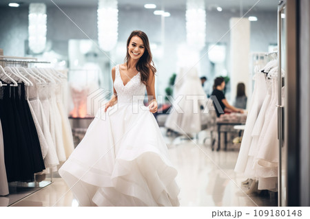 Attractive bride is trying on an elegant wedding dress in modern wedding salon 109180148