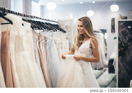 Attractive bride is trying on an elegant wedding dress in modern wedding salon 109180301