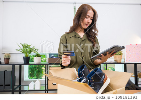 Asian young woman received online shopping parcel opening boxes to checking on digital tablet, woman holding credit card, happy female unpacking cardboard box, Shop online and delivery concept Asian young woman received online shopping parcel opening boxes to checking on digital tablet, woman holding credit card, happy female unpacking cardboard box, Shop online and delivery concept 109181393