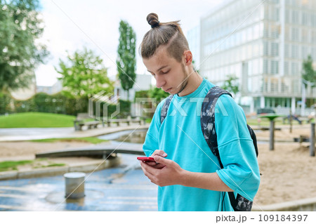 Fashionable young male with backpack using smartphone outdoors in city Fashionable young male with backpack using smartphone outdoors in city 109184397