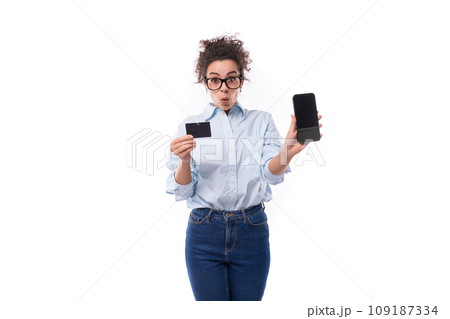 surprised young smiling stylish caucasian woman with curly hair holding plastic credit card and 109187334