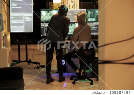 Team of cybercriminals cracking server encryption and hacking system, working on cyberterrorism at night. Young hackers doing criminal activity, stealing sensitive information. 109187397