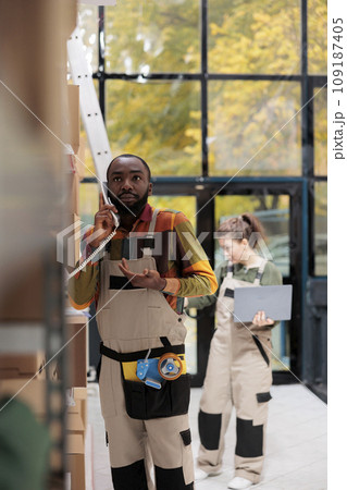Storage room worker discussing goods stock supply with warehouse manager using landline phone, working at inventory report. Employee checking clients orders in storehouse preparing packages 109187405