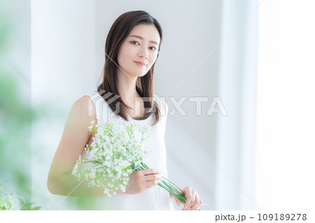 リビングでかすみ草の花束を持つ若い女性 リビングでかすみ草の花束を持つ若い女性 109189278