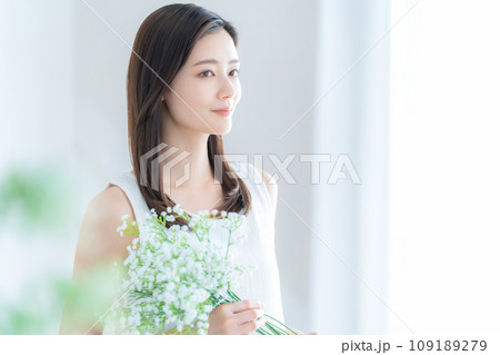 リビングでかすみ草の花束を持つ若い女性 109189279