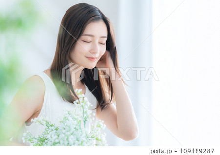 リビングでかすみ草の花束を持つ若い女性 リビングでかすみ草の花束を持つ若い女性 109189287