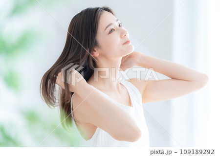 リビングの窓際でヘアケアをする若い女性 109189292