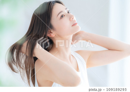 リビングの窓際でヘアケアをする若い女性 109189293